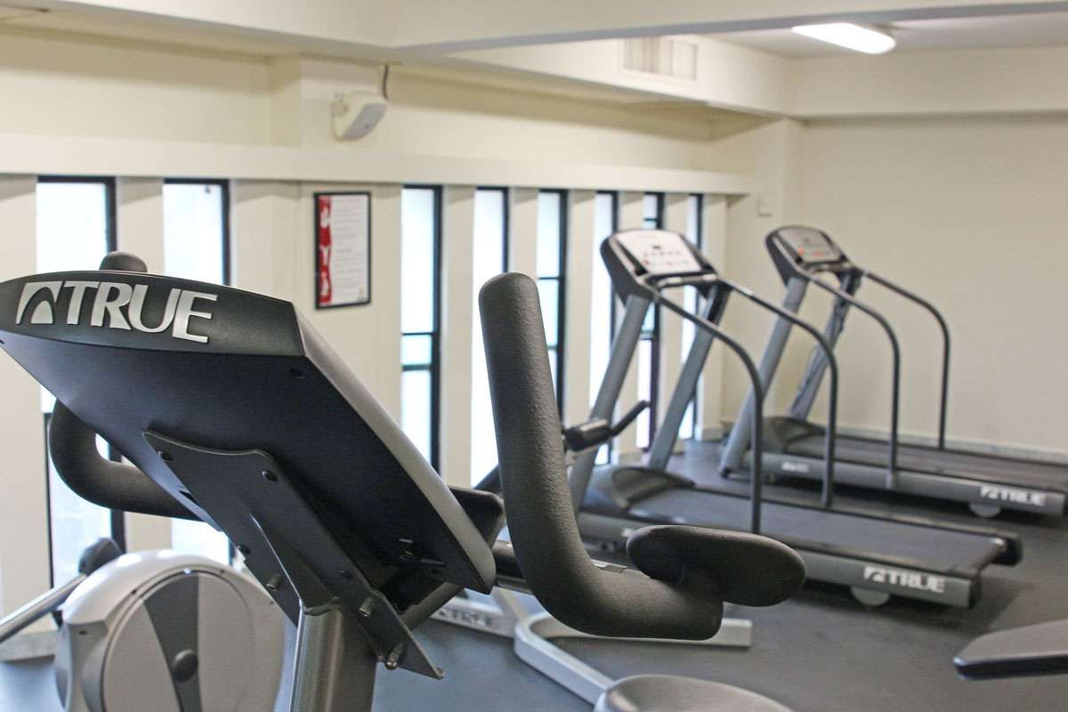 Gimnasio con cintas de correr y aparatos de ejercicio en una luminosa sala de fitness interior.