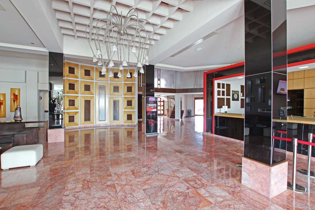 Vestíbulo moderno y vacío con suelo de mármol brillante, decoración de pared con marcos dorados y detalles en rojo y negro.