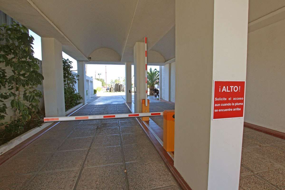Entrada cubierta con una barrera roja y blanca que bloquea el acceso, y una señal de advertencia roja en la columna.