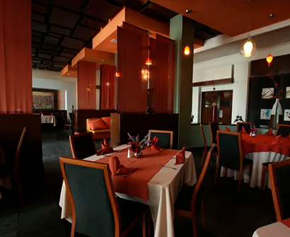 Comedor de restaurante moderno con iluminación cálida, manteles rojos y decoración de madera oscura.