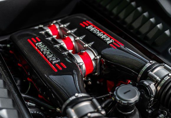 Close-up of a Ferrari engine, black with red and silver accents, carbon fiber elements.