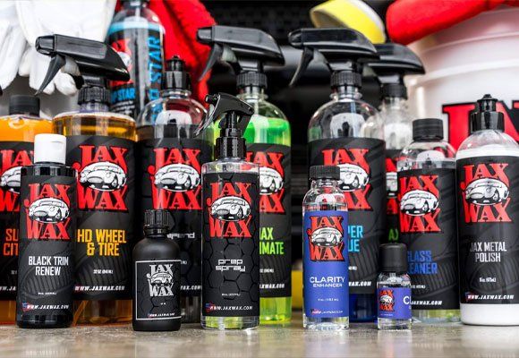 Collection of Jax Wax car detailing products. Black and red bottles, spray bottles, detailing liquids.