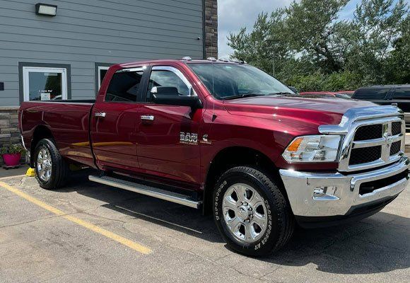 Red Dodge Ram pickup truck parked in front of a building on a sunny day.