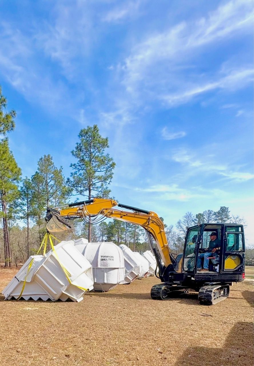 Excavator demolishing white structures in a clearing under a blue sky with trees nearby