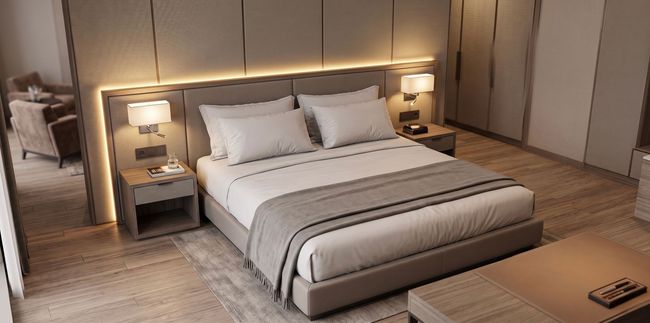 Moderne slaapkamer met een groot gestoffeerd bed, sfeervolle nachtlampjes en een neutrale beige inrichting. 5 sterren de luxe hotel 