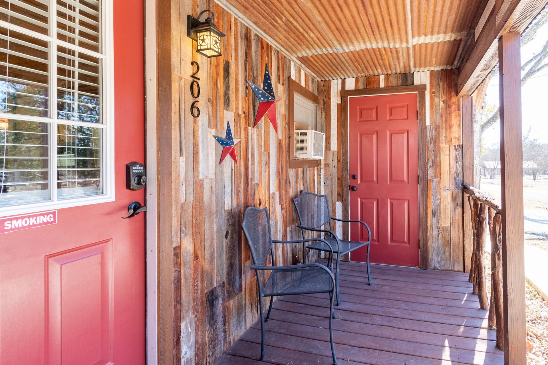 A porch with a red door and chairs on it.