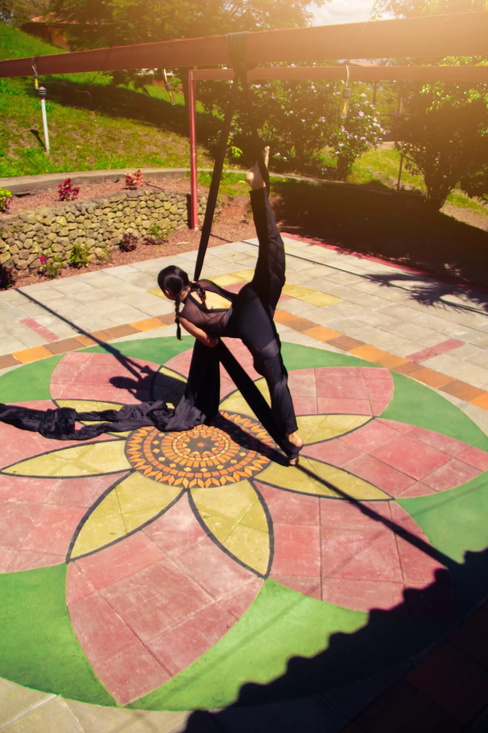 Person doing a yoga pose on a colorful flower mural in a sunny outdoor garden