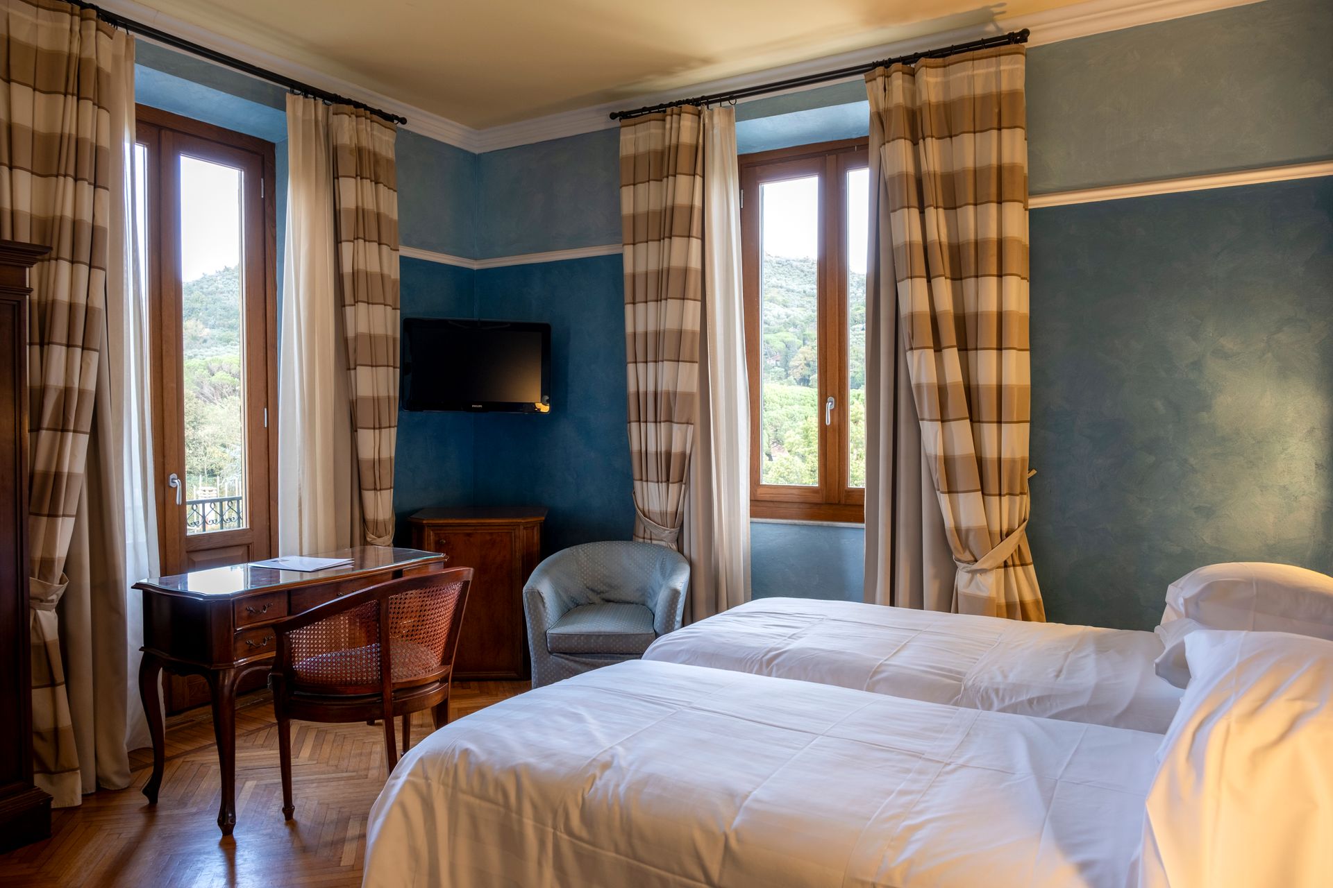 Гостиничный номер с двумя кроватями, письменным столом и телевизором.