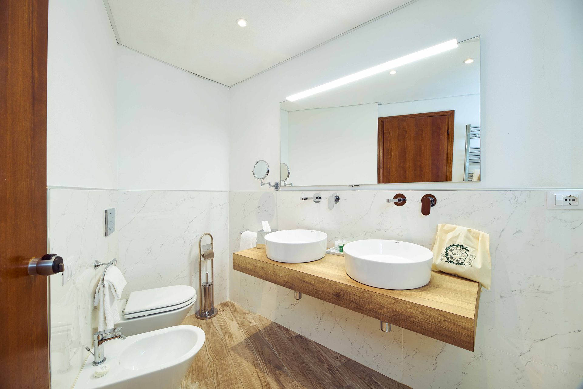 Ванная комната с двумя раковинами, унитазом и зеркалом.