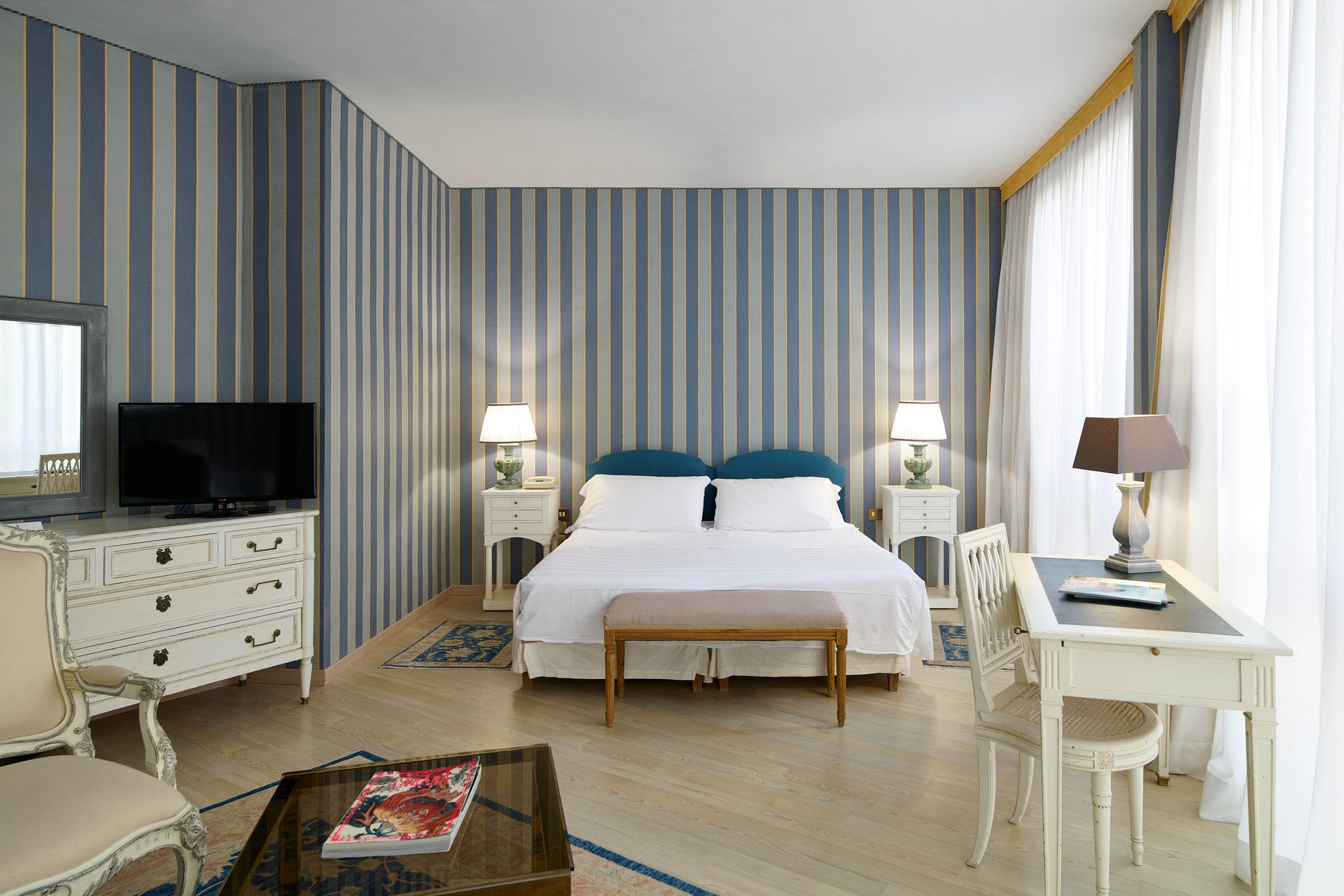 Una stanza d'albergo con un letto, una scrivania, delle sedie e una televisione.