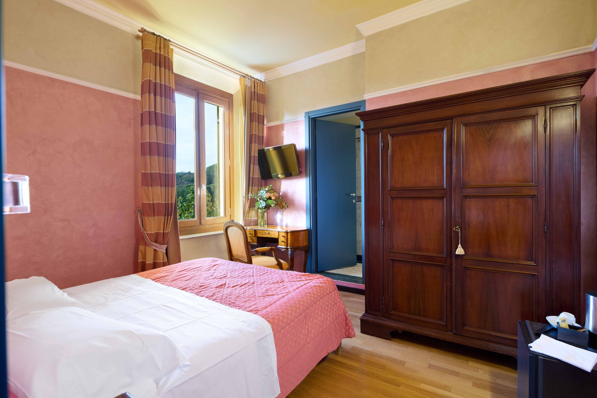 Гостиничный номер с кроватью, шкафом, письменным столом и окном.