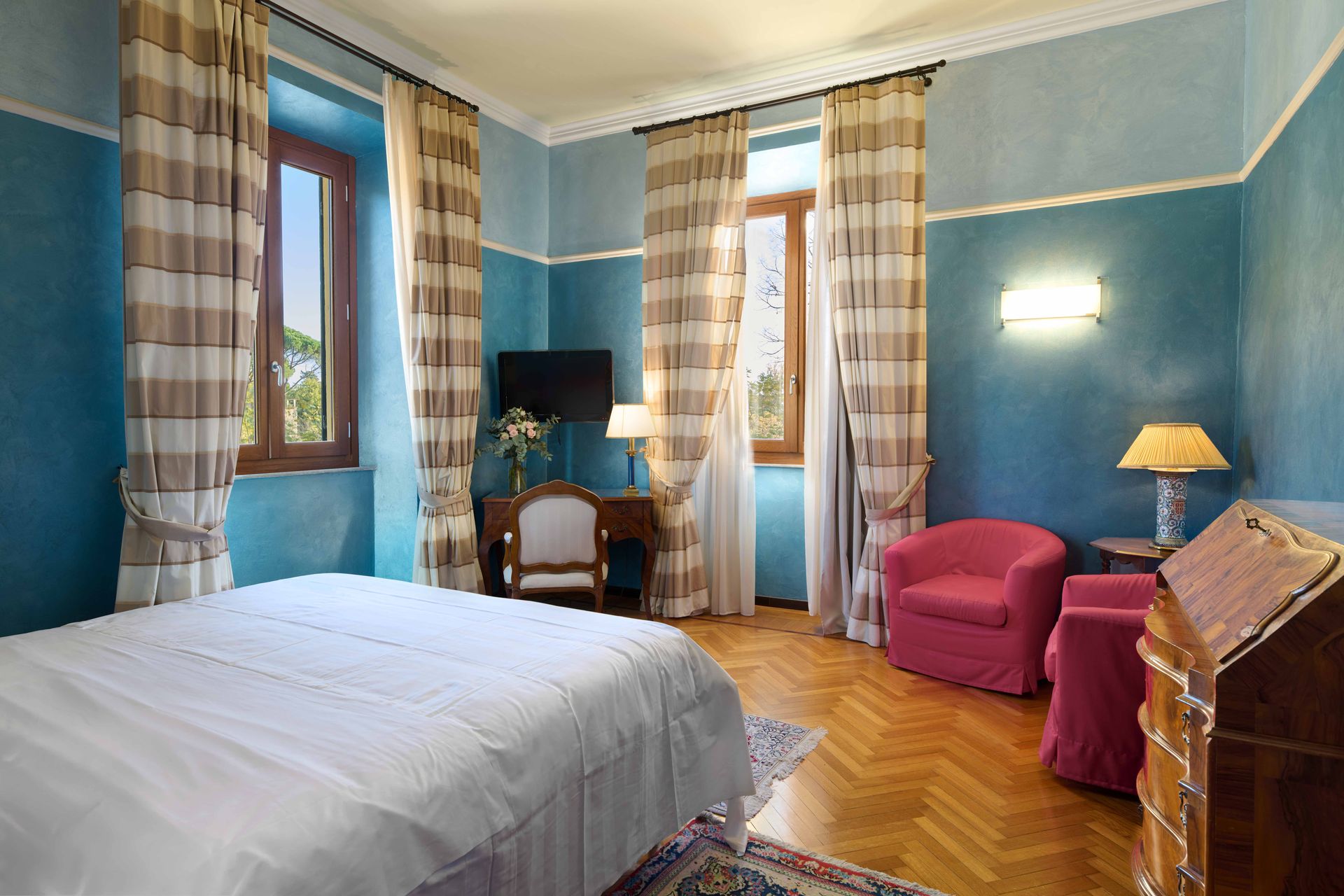 Гостиничный номер с кроватью, стульями, письменным столом и телевизором.