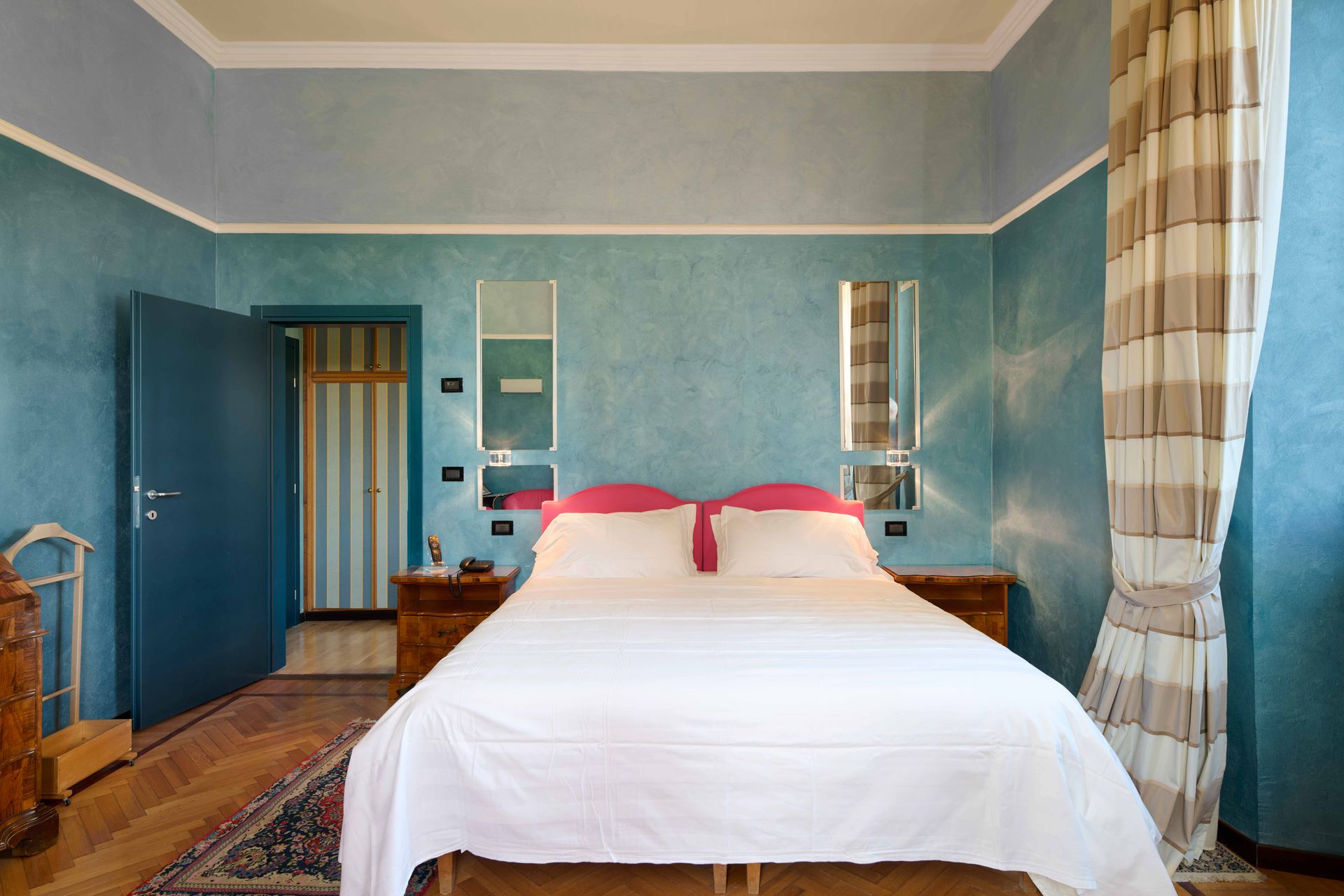 Спальня с синими стенами и кроватью с белыми простынями