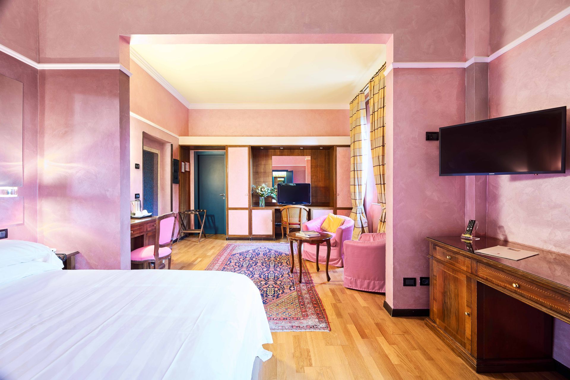 Гостиничный номер с кроватью, письменным столом, стульями и телевизором.