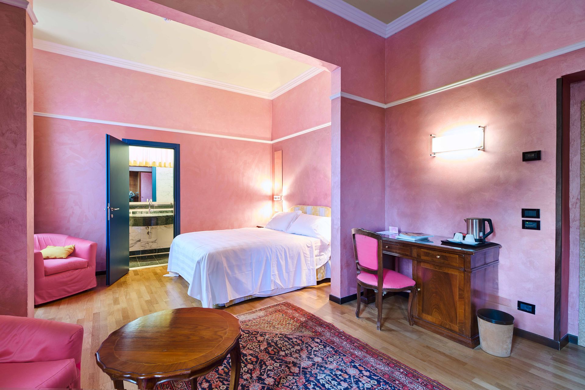 Гостиничный номер с розовыми стенами и кроватью.
