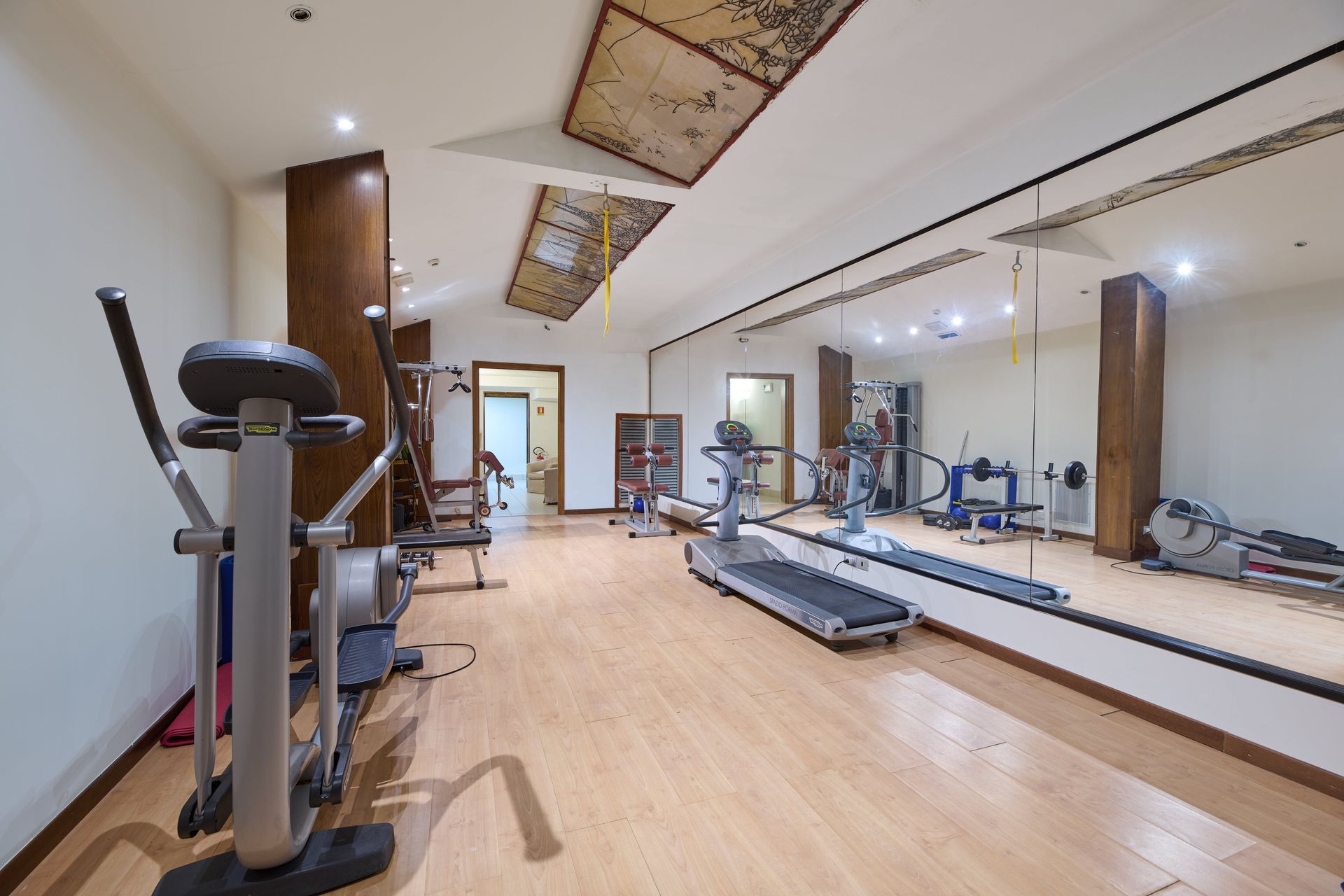 Una palestra con tapis roulant, cyclette e un grande specchio.