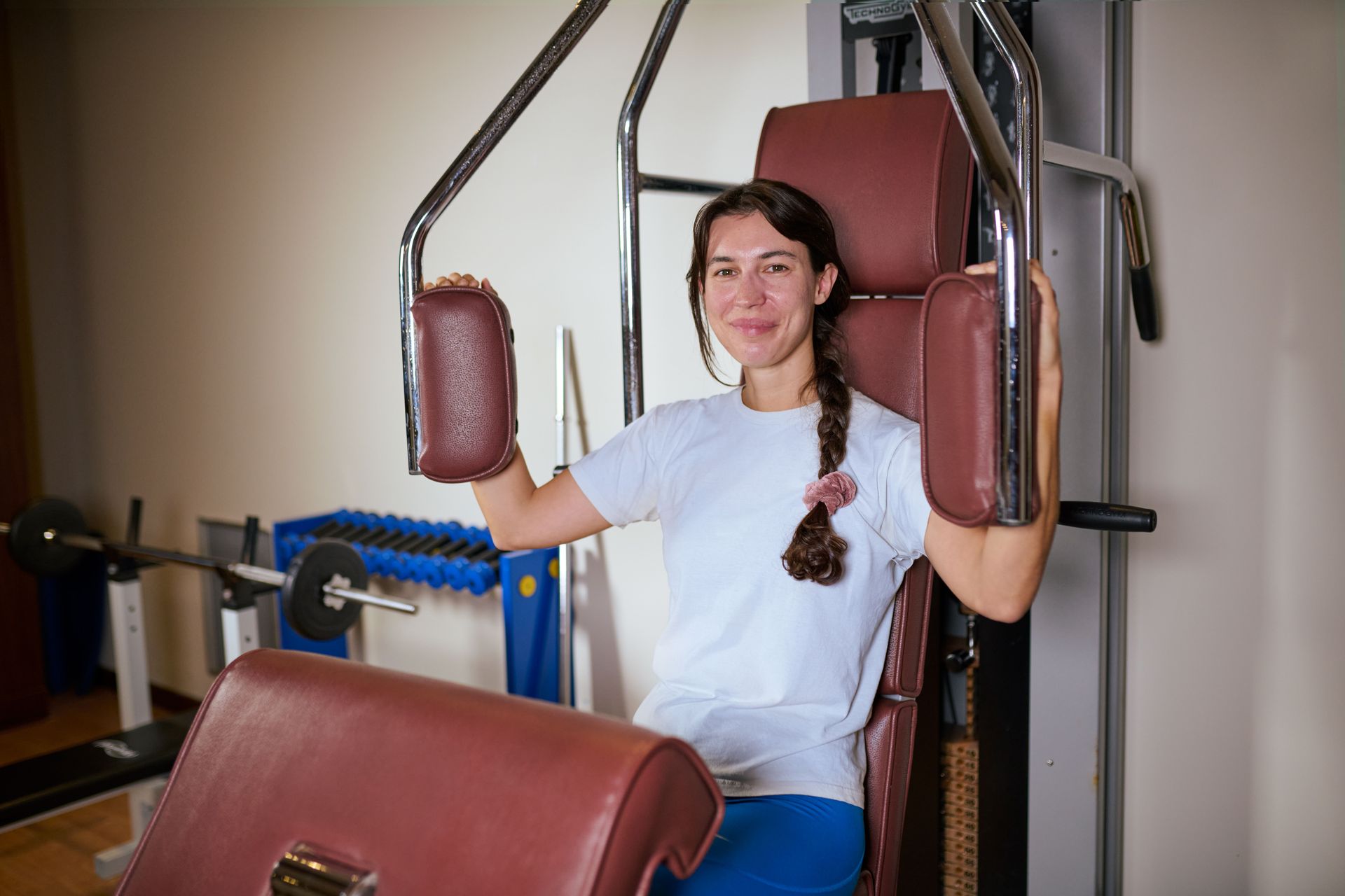 Женщина сидит на тренажере в спортзале.