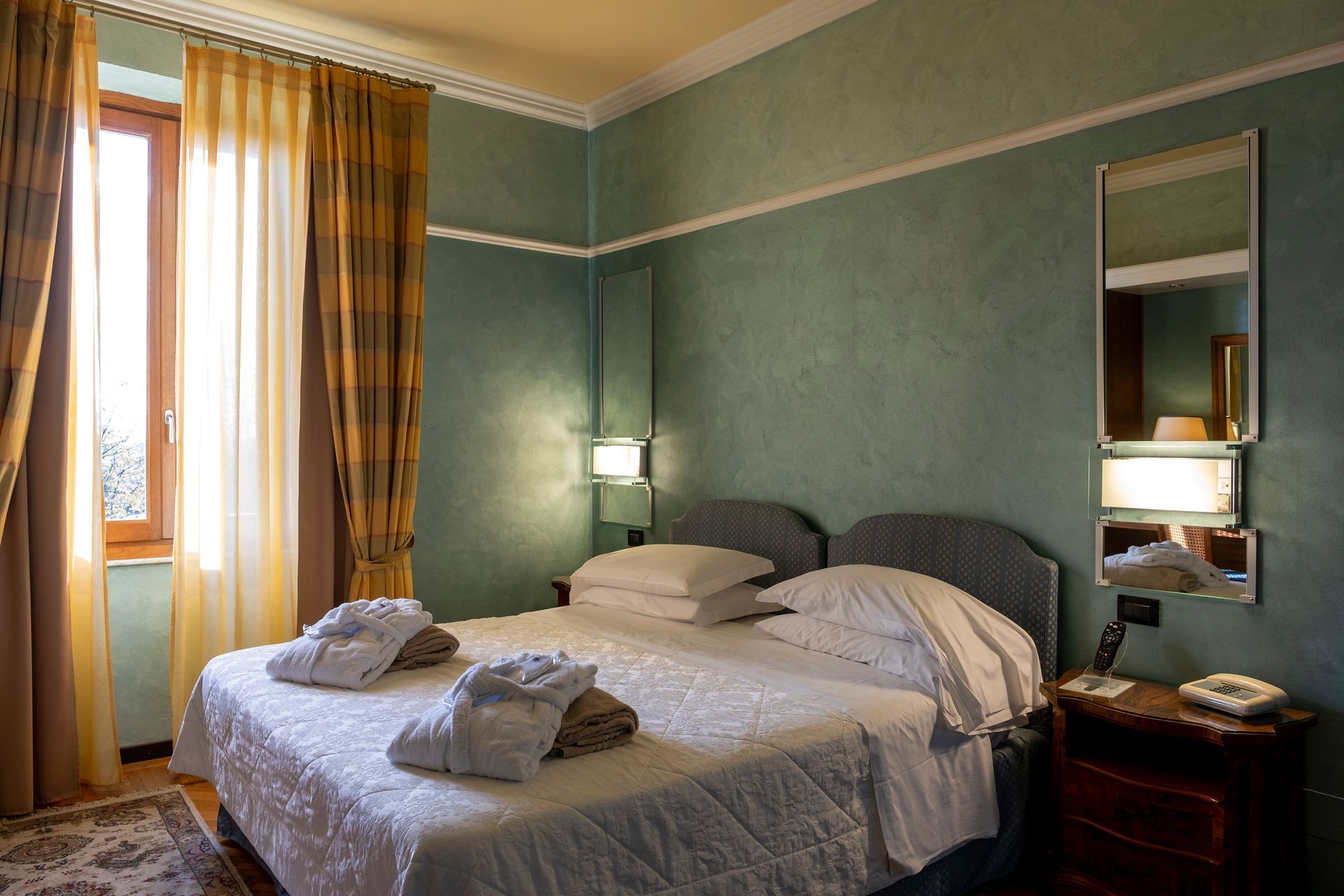 Una stanza d'albergo con due letti e una finestra