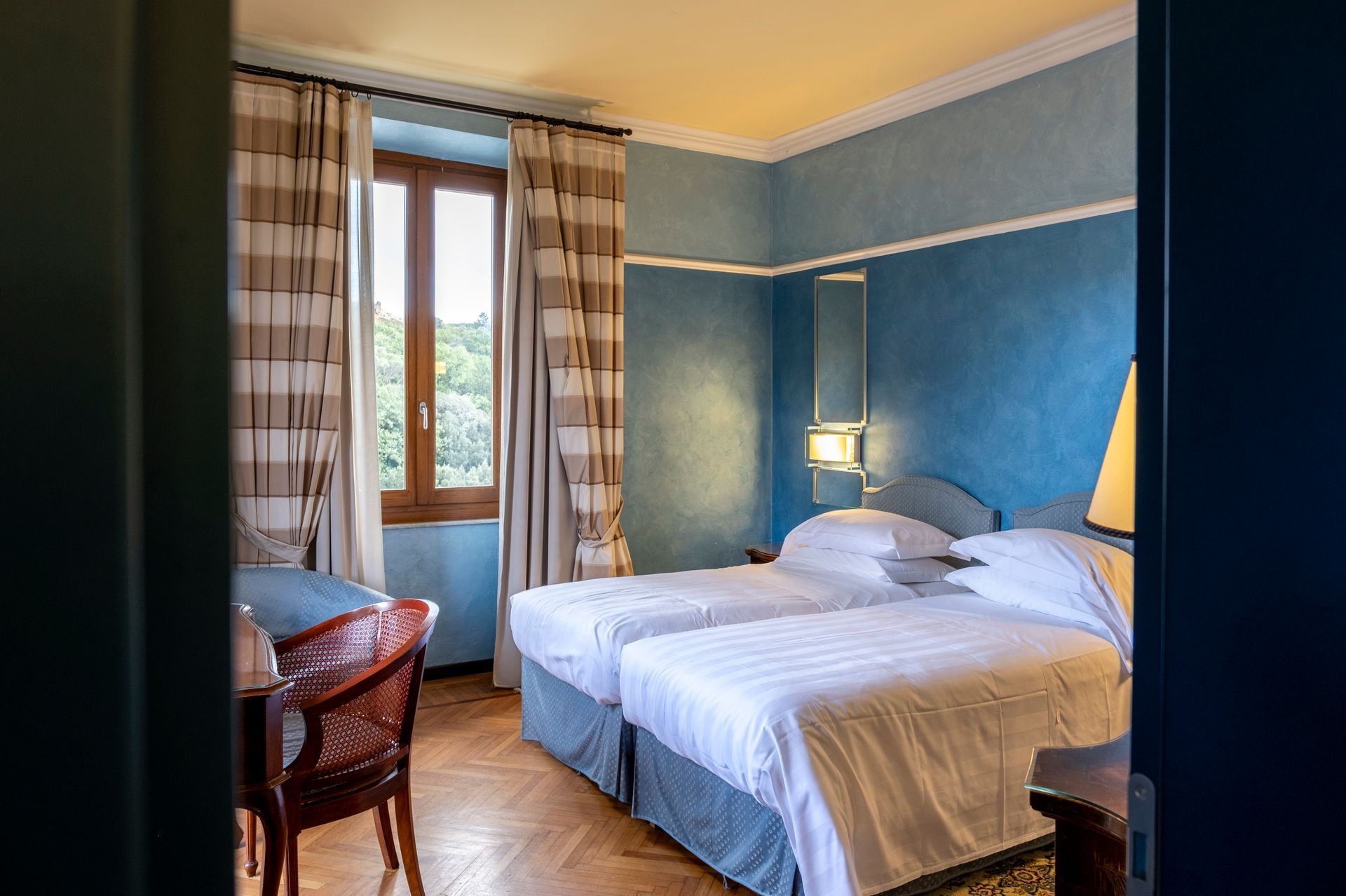 A hotel room with two beds , a desk and a window.