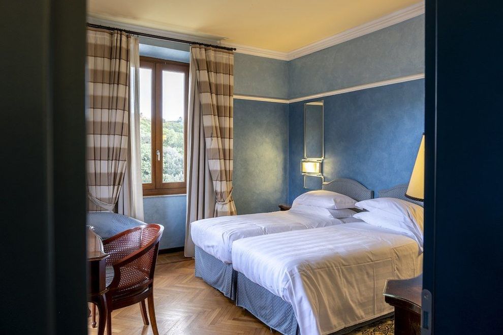 Una stanza d'albergo con due letti, una scrivania e una finestra.