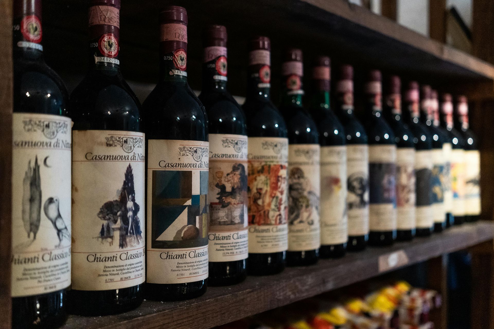 Several bottles of wine are lined up on a wooden shelf