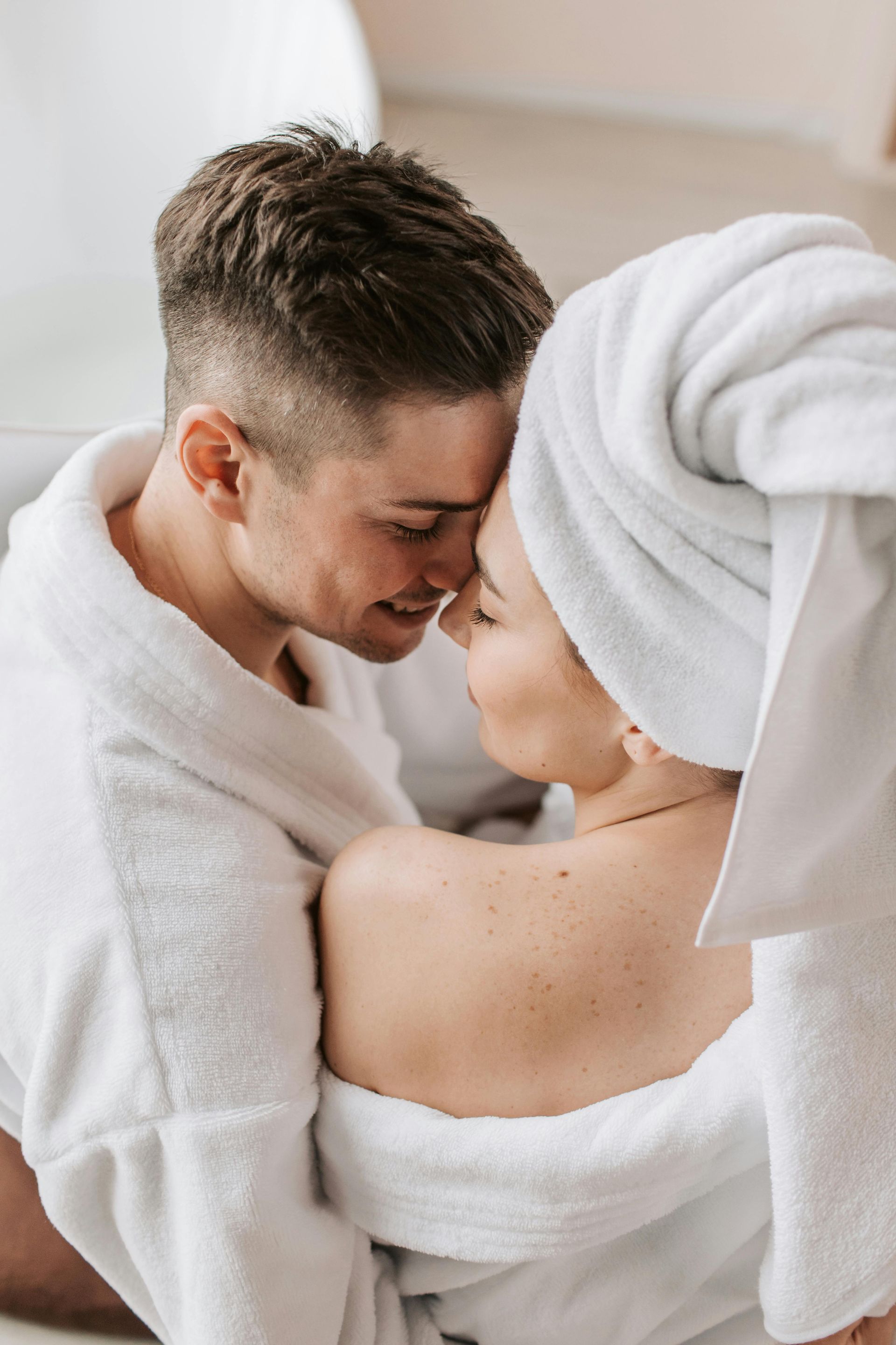 Un uomo e una donna con degli asciugamani avvolti intorno alla testa si baciano.
