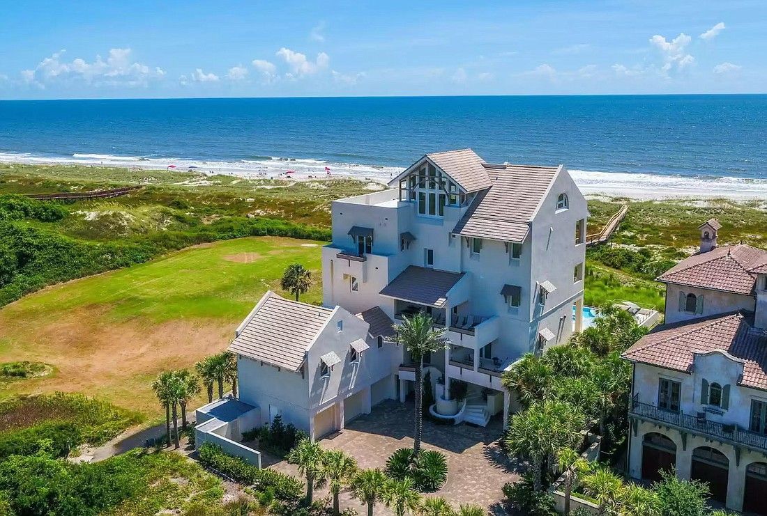 Oceanfront multi-story white house with blue sky and ocean view.