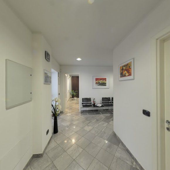 Luminoso corridoio bianco con pavimento piastrellato che conduce a una moderna zona salotto e opere d'arte incorniciate alle pareti.