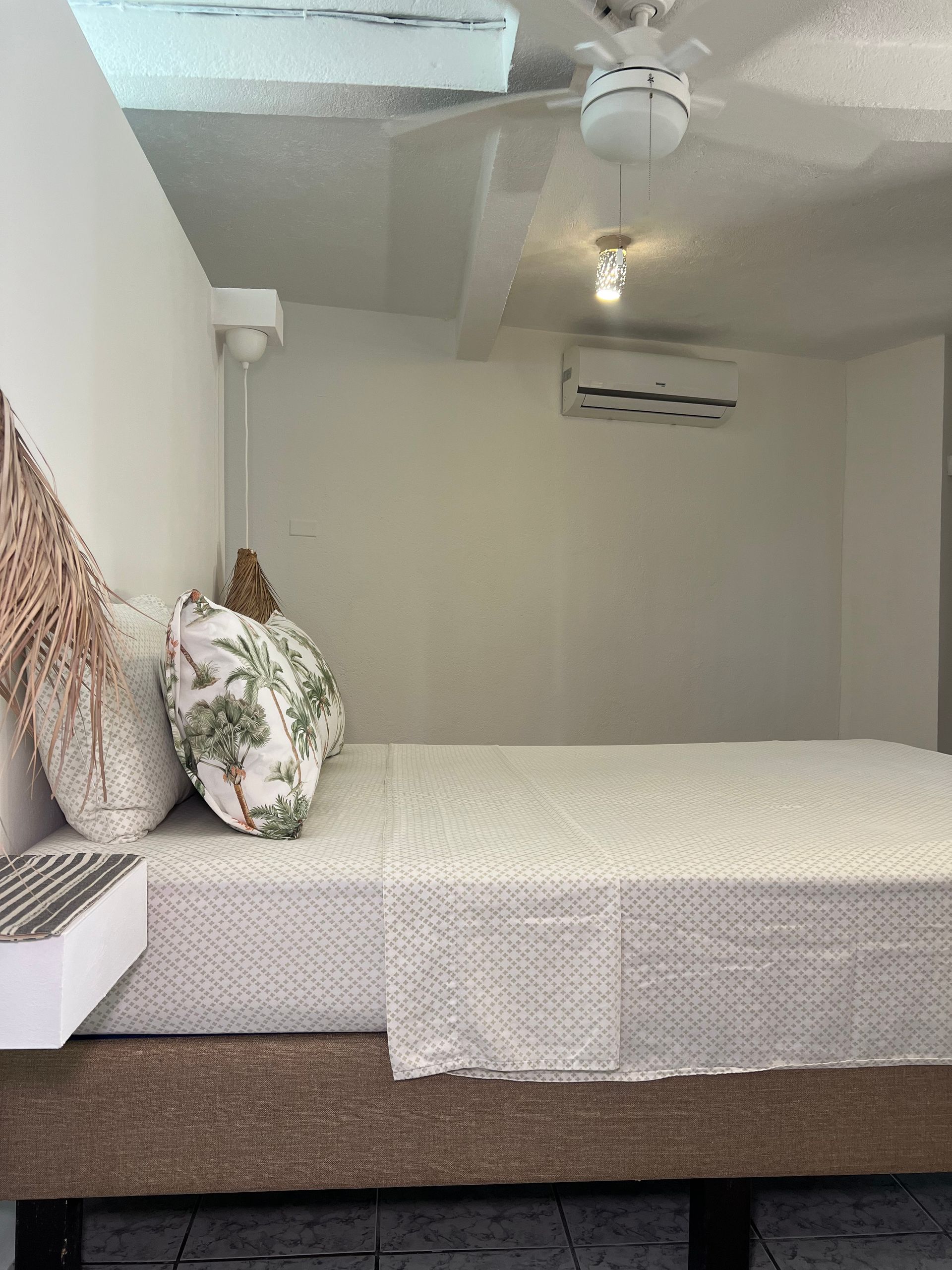 A bedroom with a bed , ceiling fan and air conditioner.