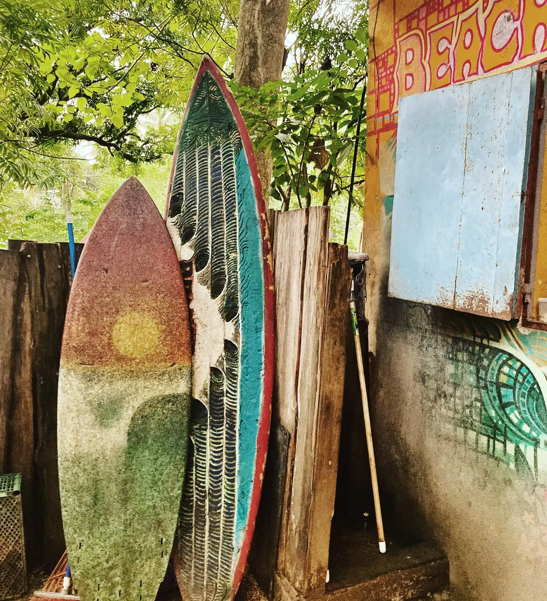 Two surfboards are leaning against a wooden fence.