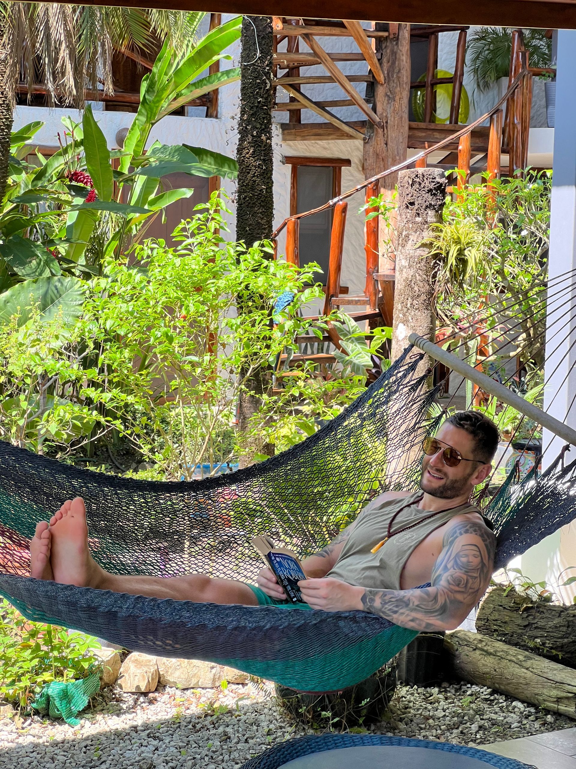 A man is laying in a hammock looking at his phone.