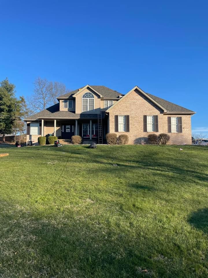 Brick two-story house with green lawn under a clear blue sky.