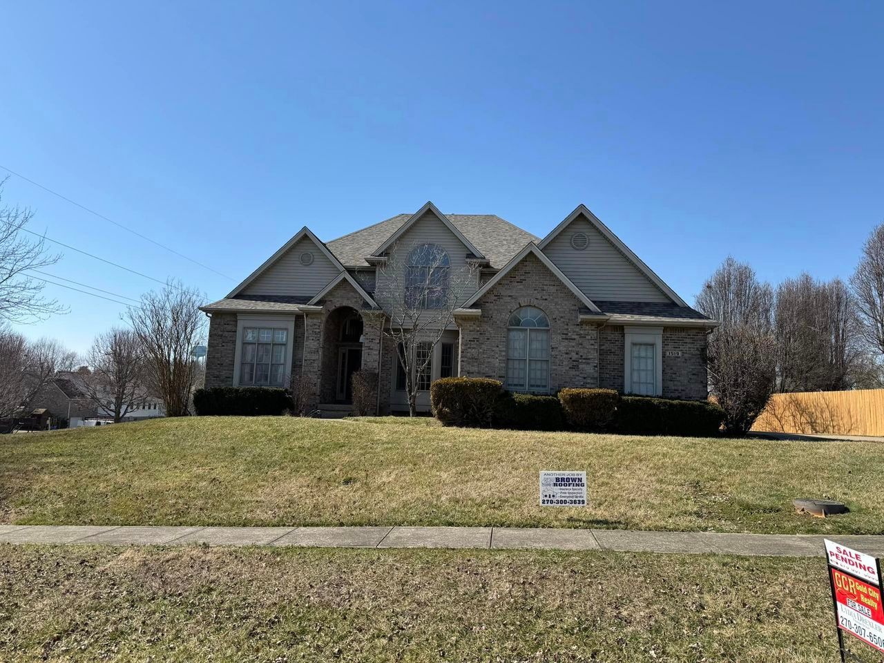Brick house with a sloped roof, on a grassy hill, under a clear blue sky.
