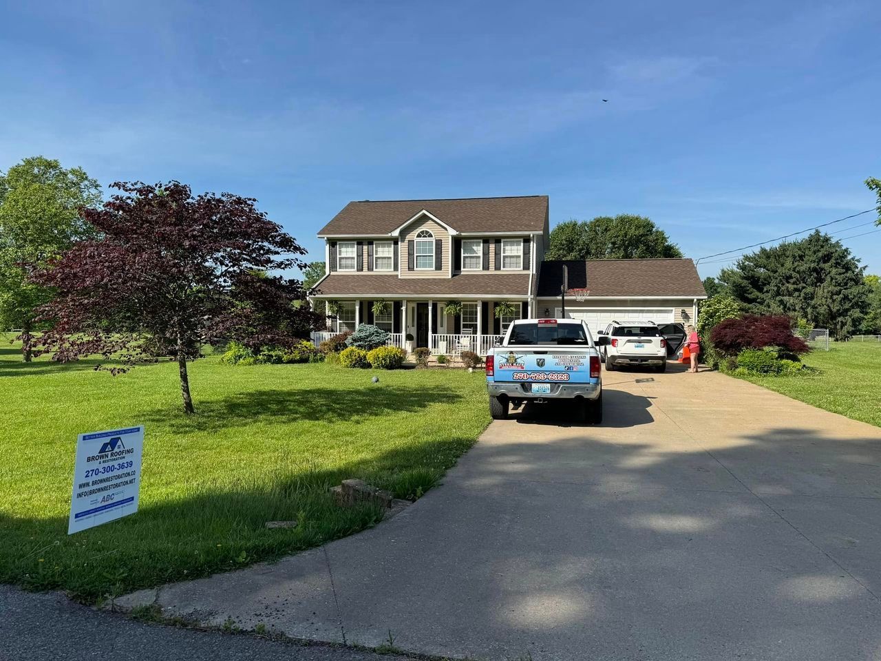 Two-story house with a driveway. A truck is parked in front of the garage. Sunny day.