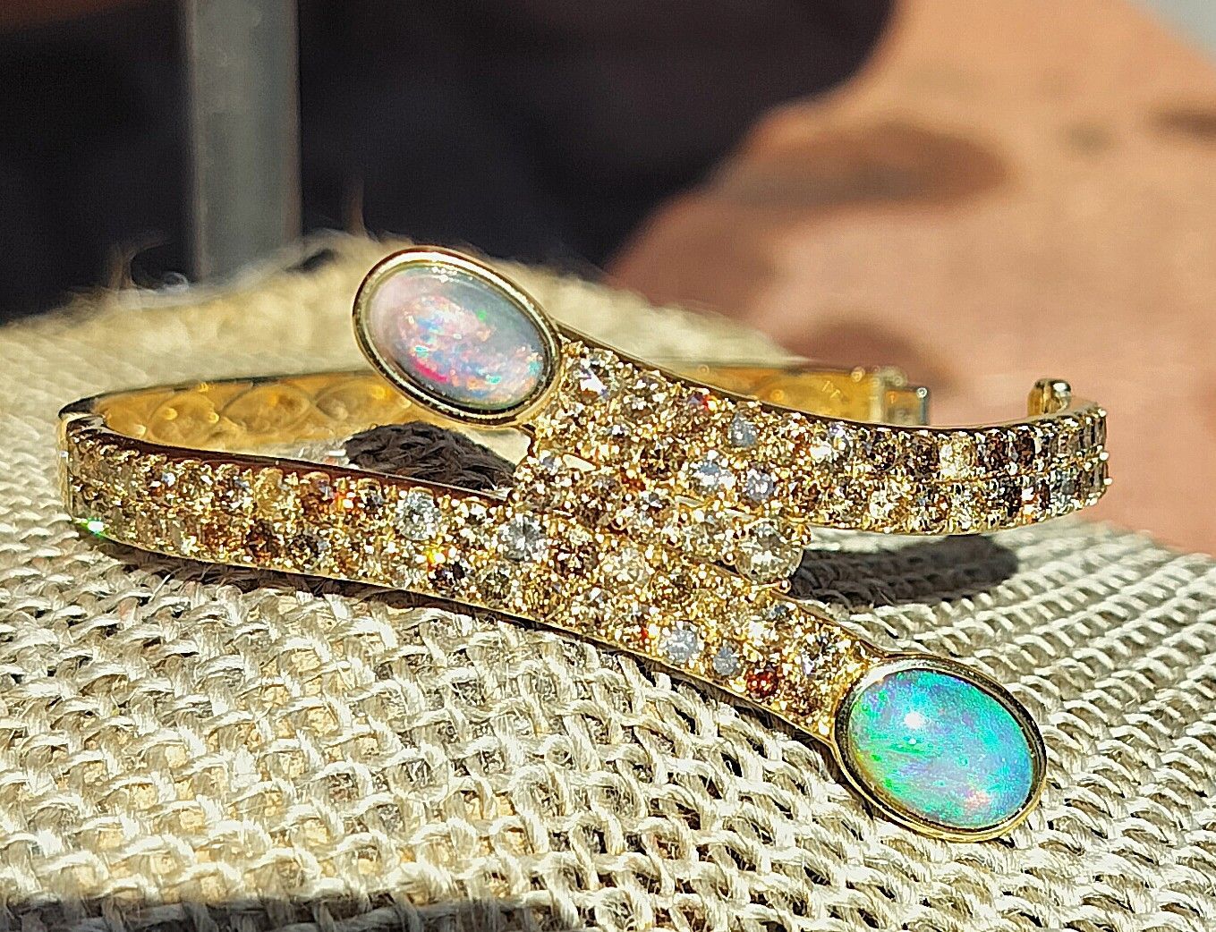 Gold jeweled bracelet with two opal-like stones on textured fabric