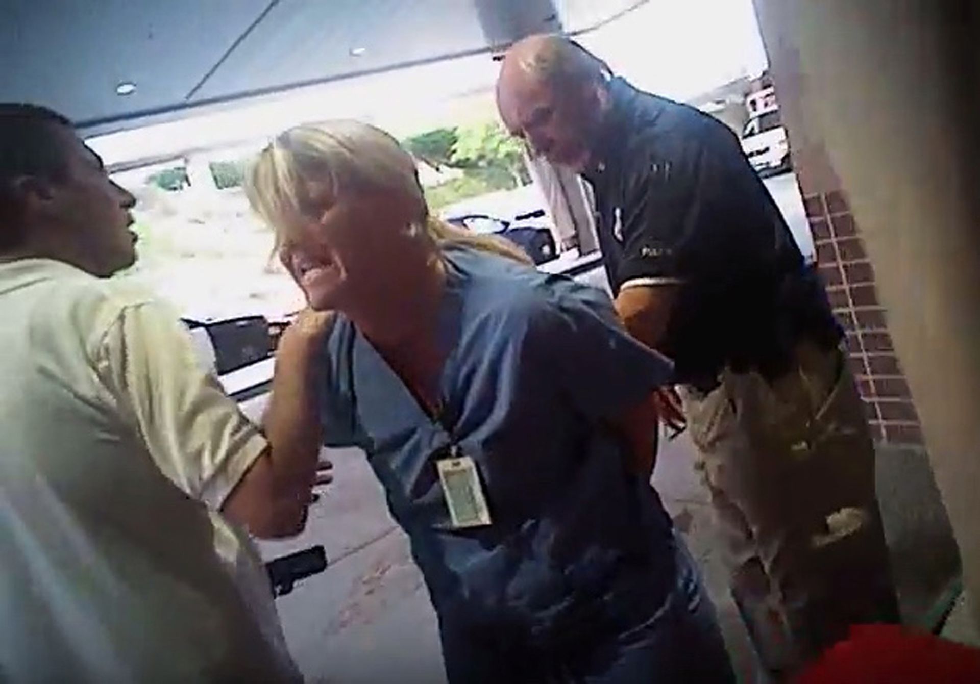 People arguing outside, woman in scrubs yelling, man in white shirt, and man in black shirt.