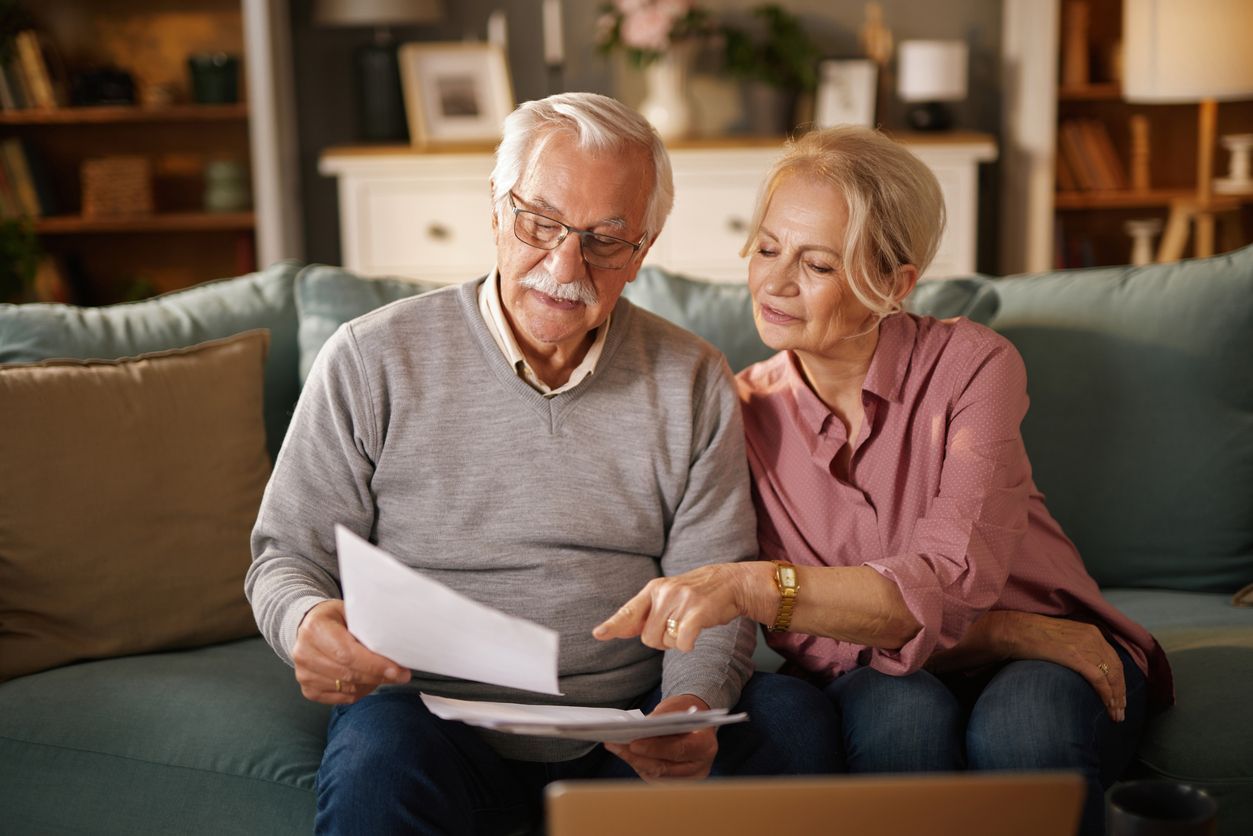 Two people on a couch reviewing papers together in a cozy living room