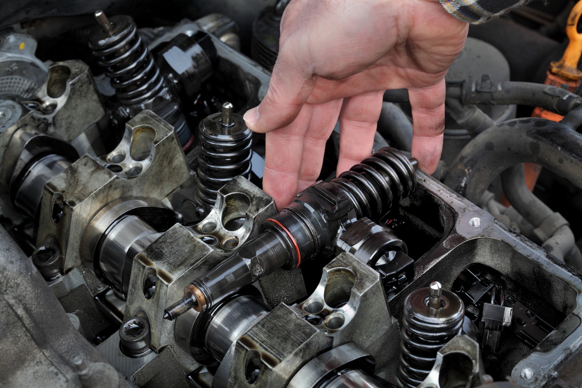 Close-up of a mechanic's hand removing injectors from the cylinder head. Close-up of a mechanic's hand removing injectors from the cylinder head.