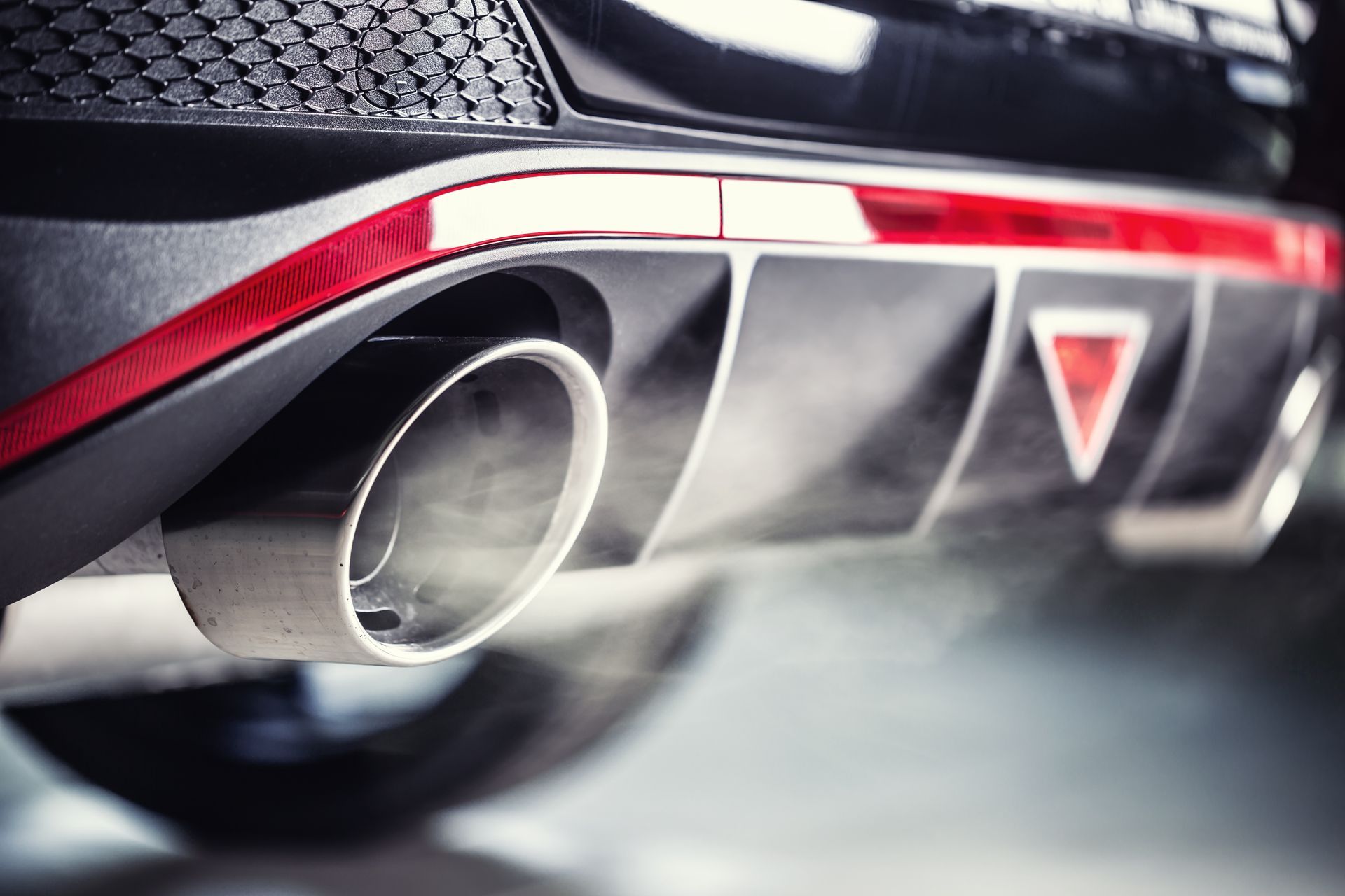 A close-up of leaking gases from an exhaust of a diesel car.