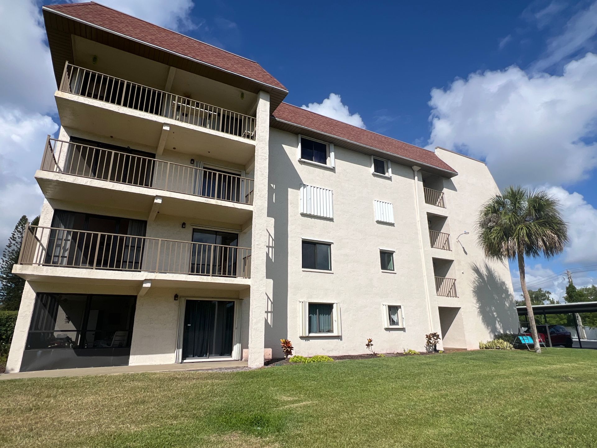 White condominium home with red roofs and green grass.