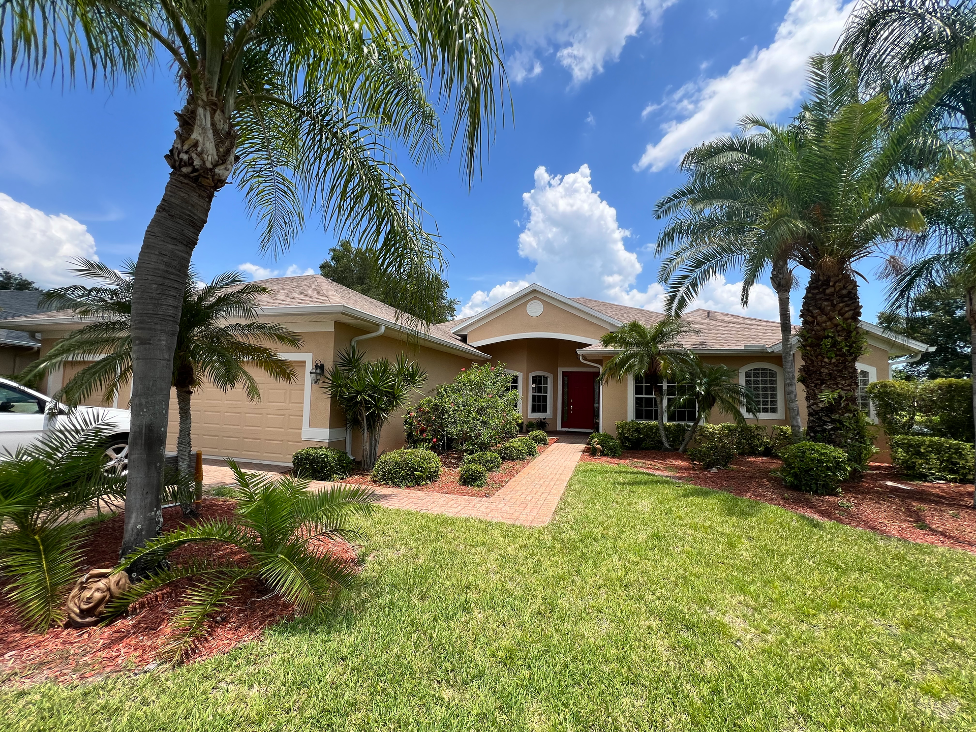 One story home archway over the front door with palm trees, and clouds