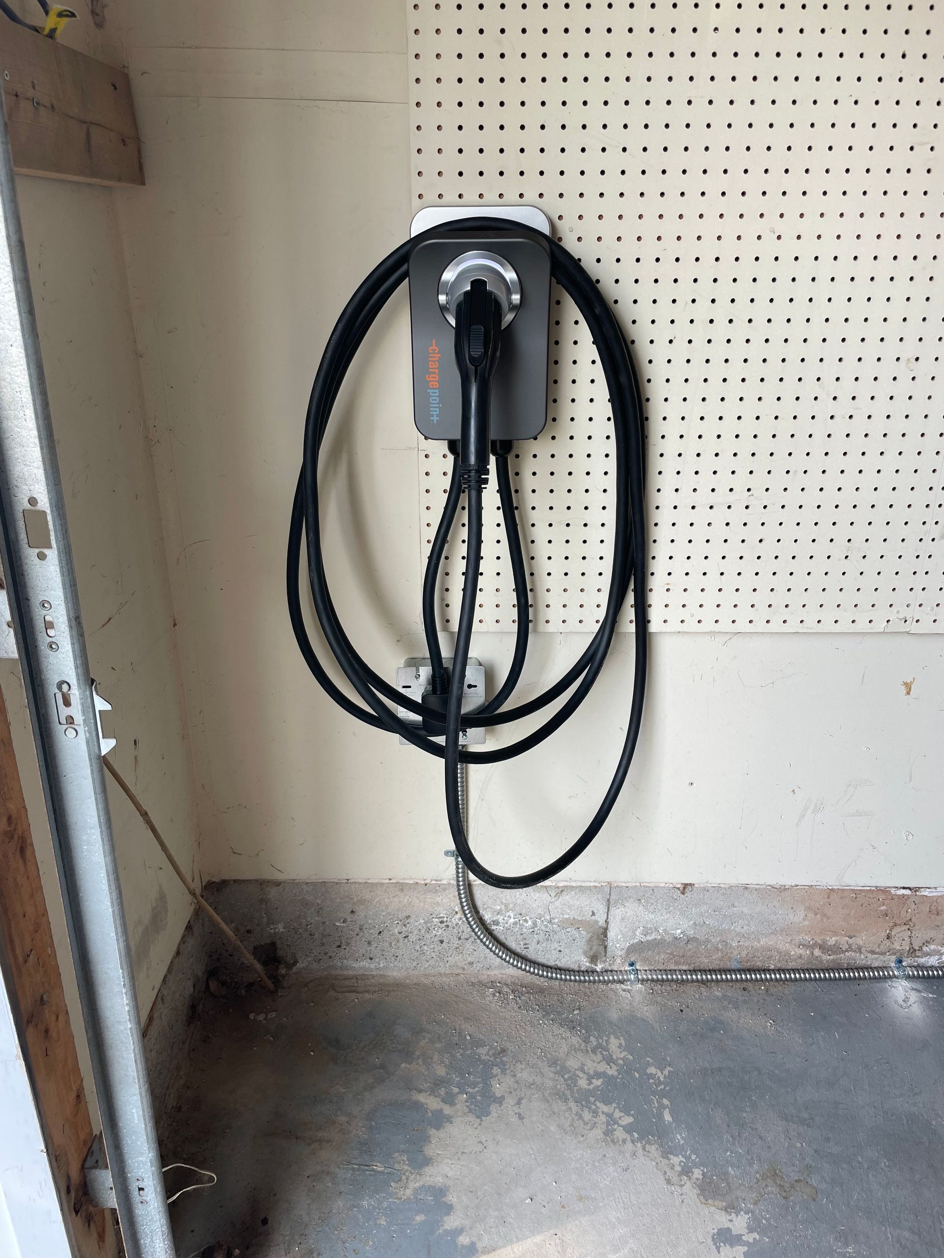 A black cord is connected to a charger on a wall.
