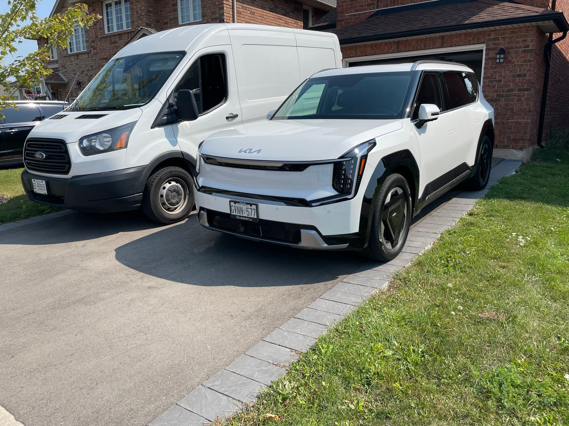 Two white cars are parked next to each other in a driveway.