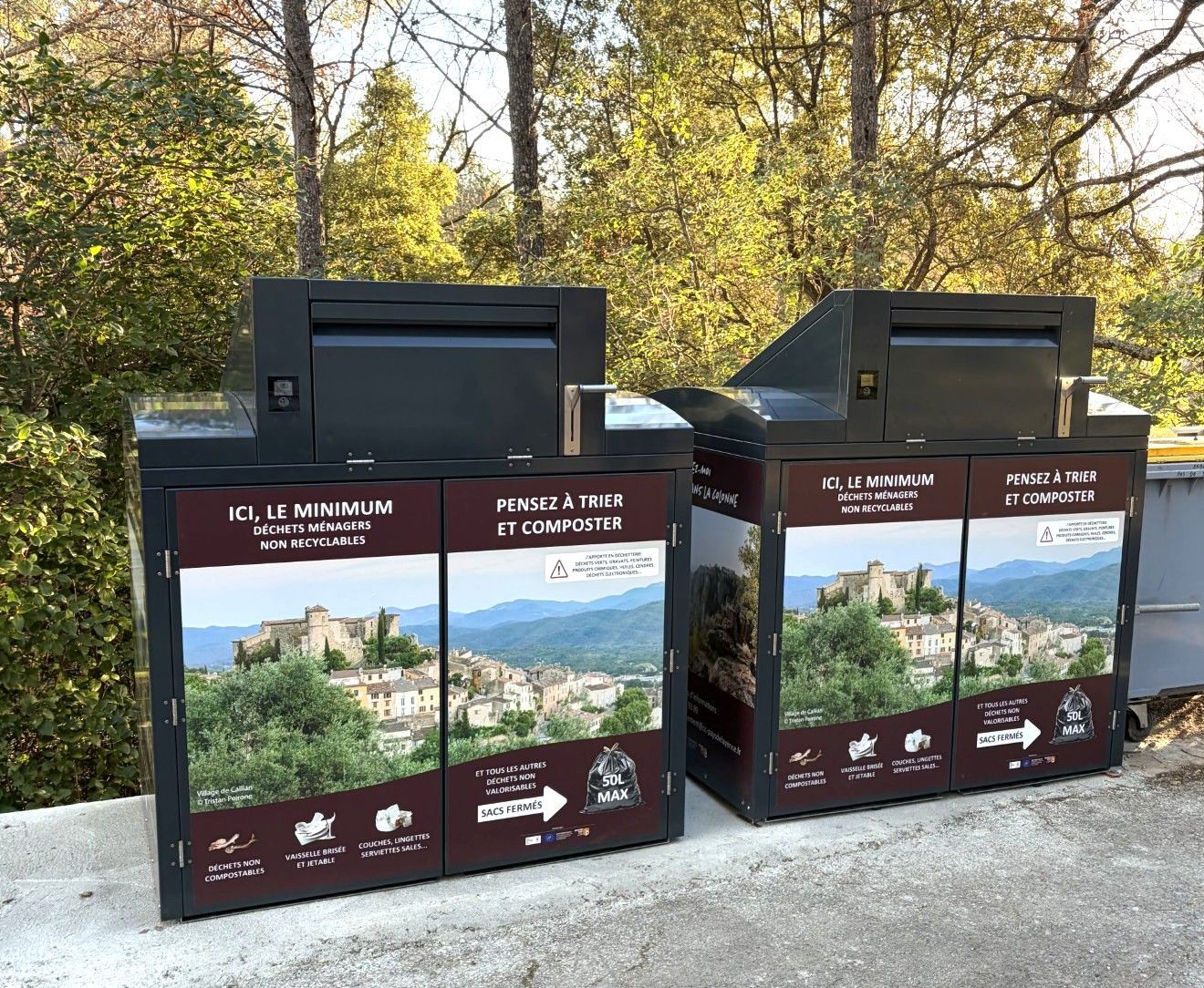 Deux poubelles de recyclage sombres ornées de photos de paysages urbains. Arbres et ciel en arrière-plan.