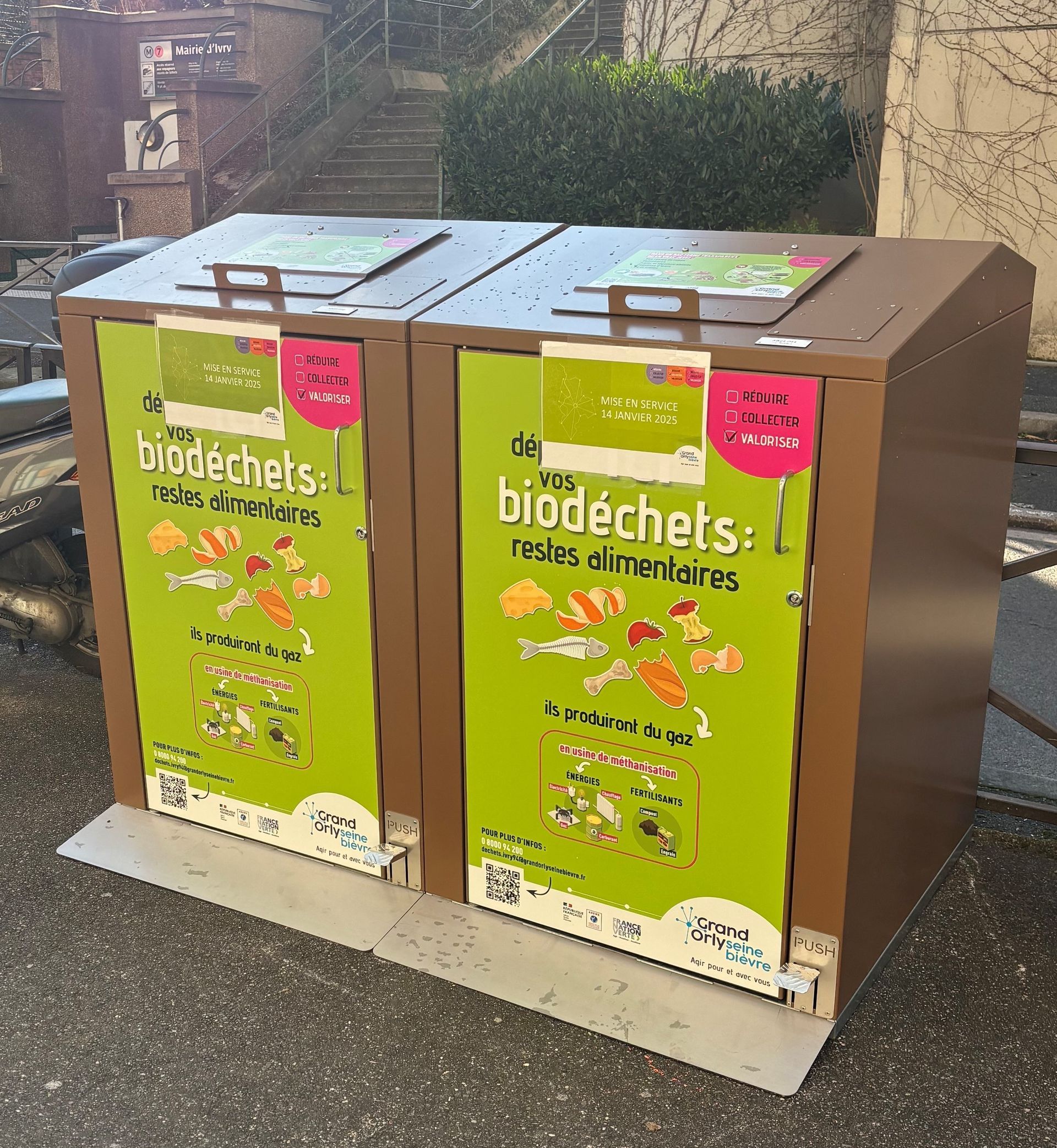 Deux poubelles de recyclage marron avec des étiquettes vertes et roses portant la mention « biodéchets ».