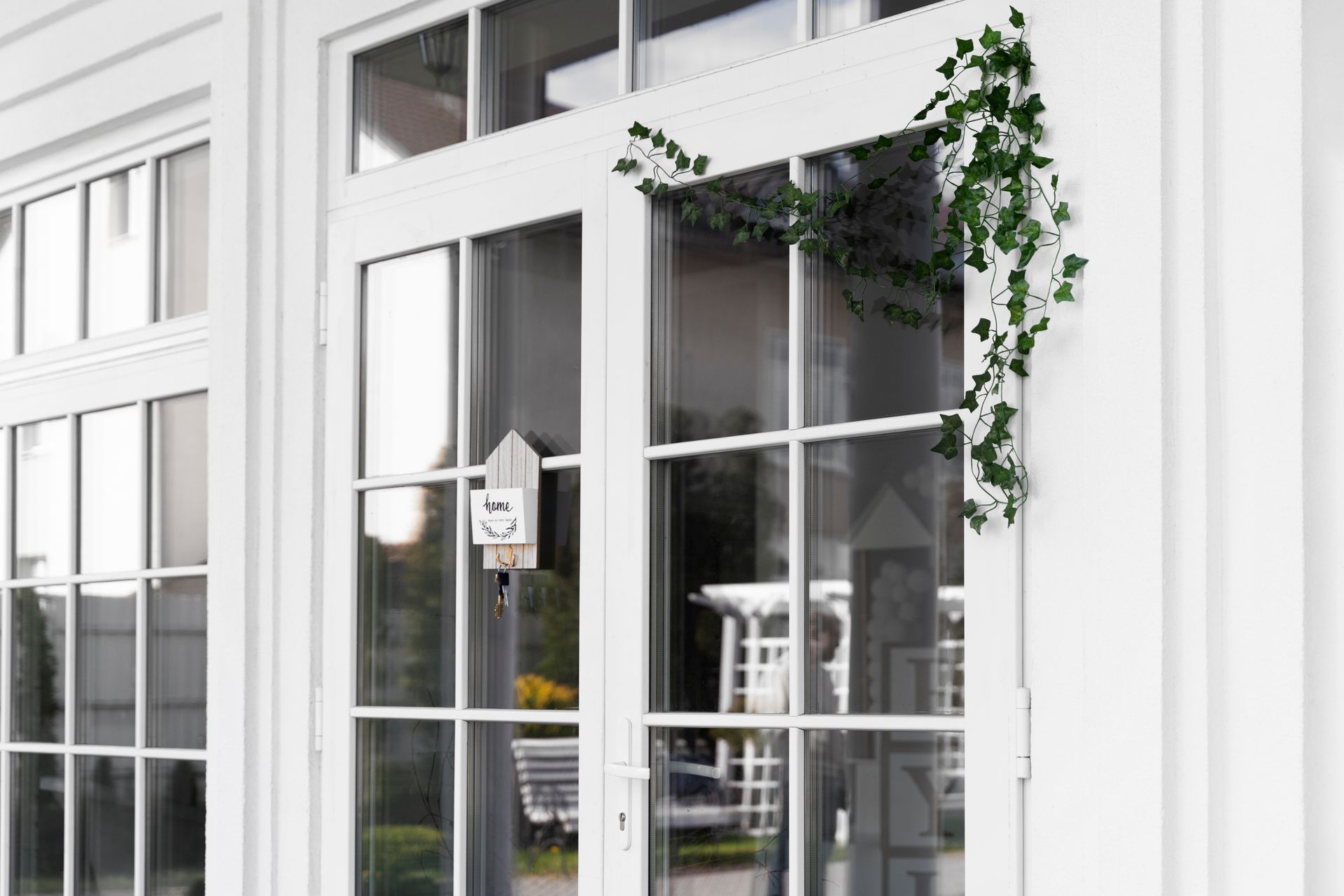 White french doors with attached greenery and a bird feeder.