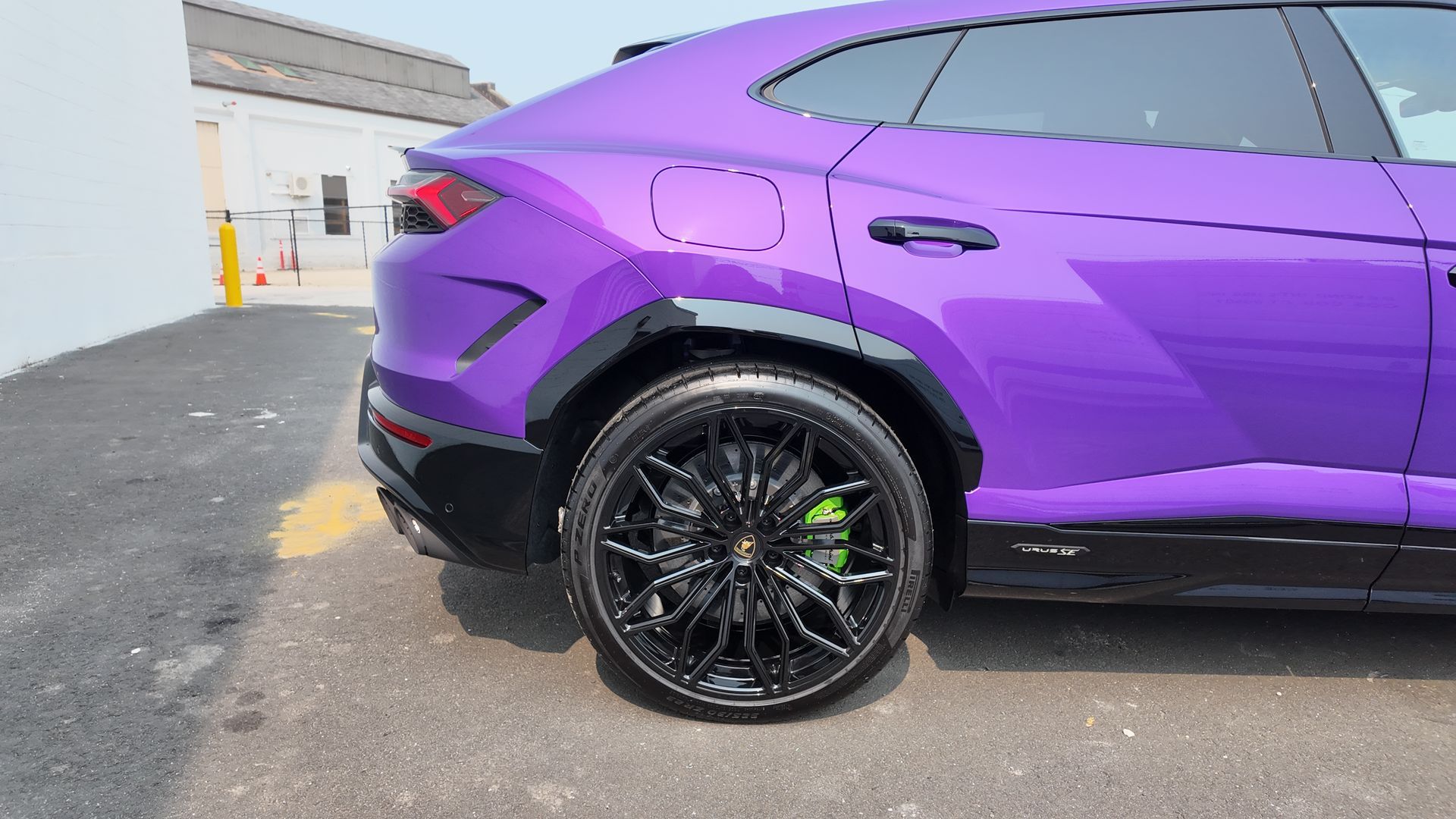 Purple Lamborghini SUV with black wheels and green brake calipers.