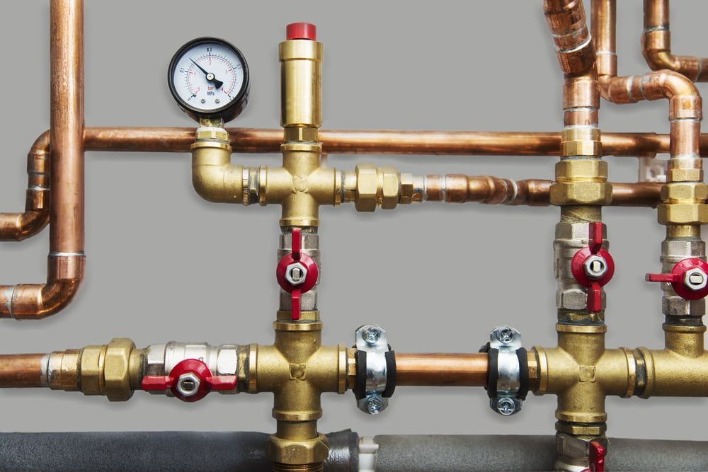 A close up of copper pipes with a gauge on top