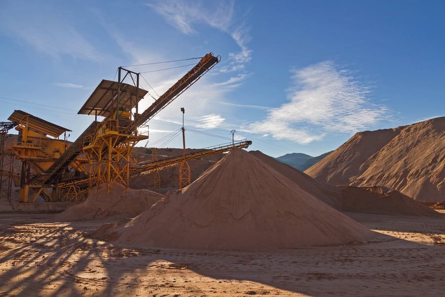 A pile of sand is sitting in the middle of a dirt field.