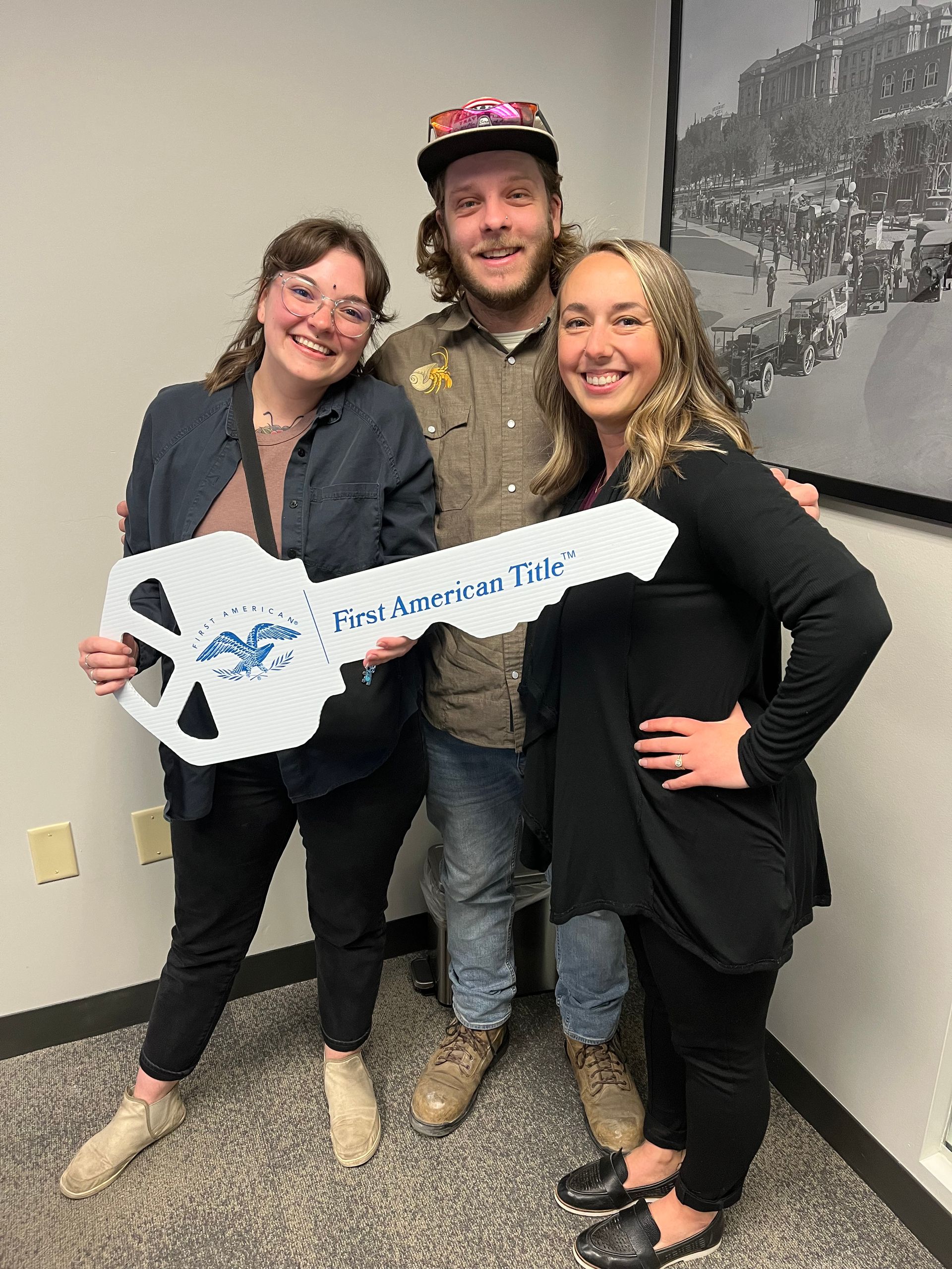 Three people holding a giant key